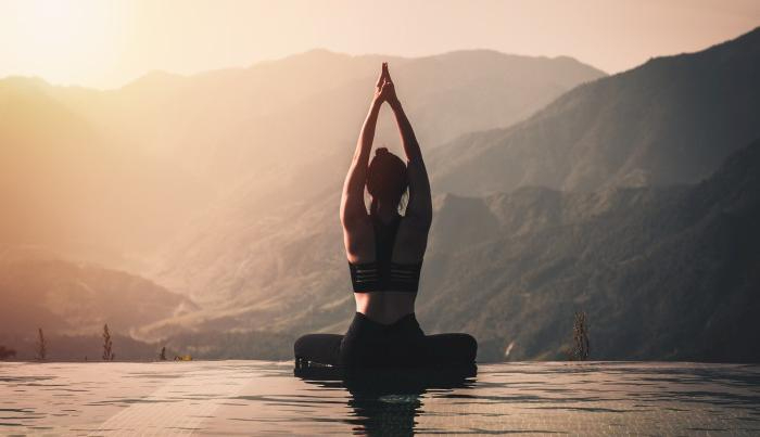 Beautiful Attractive Asian woman practice yoga Lotus pose on the pool above the Mountain peak in the morning in front of beautiful nature views,Feel so comfortable and relax in holiday,Warm tone